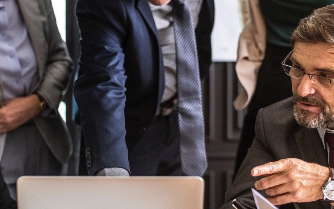 a group of men examining data on a laptop